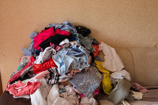 Vista frontal de la ropa dispersa en el sofá en casa
 - Foto, imagen