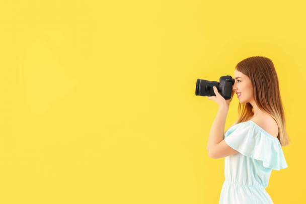 Young female photographer on color background - Foto, afbeelding