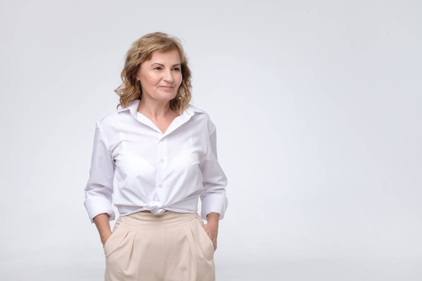 Beautiful mature business woman standing in white modern shirt looking aside. - Photo, Image