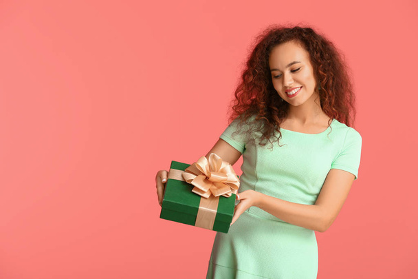 Beautiful young woman with gift on color background - Fotó, kép