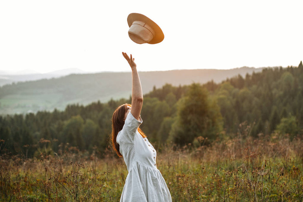 stylisches unbeschwertes Boho-Girl wirft bei sonnigem Wetter seinen Hut in den Himmel  - Foto, Bild
