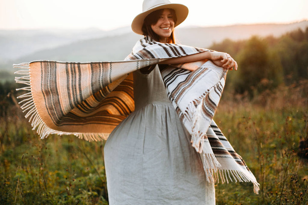 Счастливая женщина-хипстер в пончо и шляпе, наслаждающаяся путешествиями по ровным дорожкам
 - Фото, изображение