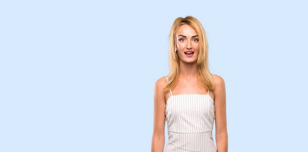 Jonge blonde vrouw met verrassing gezichtsuitdrukking over geïsoleerde blauwe achtergrond - Foto, afbeelding