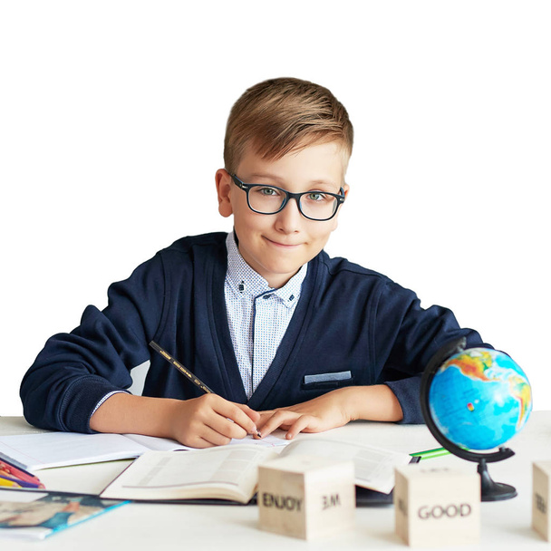 um menino com óculos fazendo uma lição na aula fazendo uma tarefa, de volta à escola, estudante com uma mochila na escola, uniforme escolar
 - Foto, Imagem
