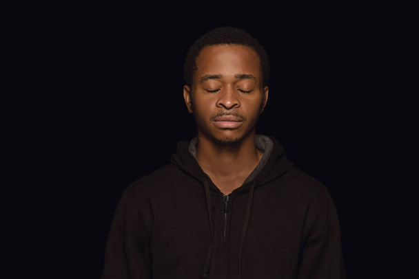 Κοντινό πορτρέτο του νεαρού άνδρα που απομονώνεται σε μαύρο στούντιο φόντο - Φωτογραφία, εικόνα