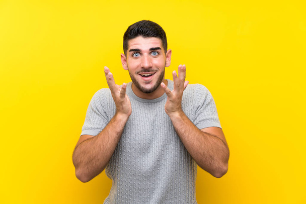 Young handsome man over isolated yellow background with surprise facial expression - Foto, Imagen