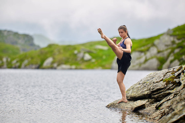 Kickboxer girl training by lake in mountains at daytime - Foto, Imagen