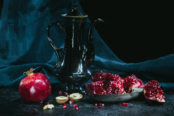 painted teapot near pomegranates and walnuts on black   - Valokuva, kuva