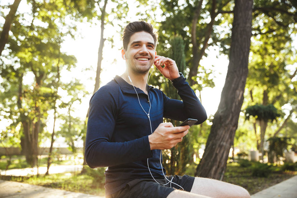 Portrait of attractive athletic man listening to music with earp - Foto, afbeelding