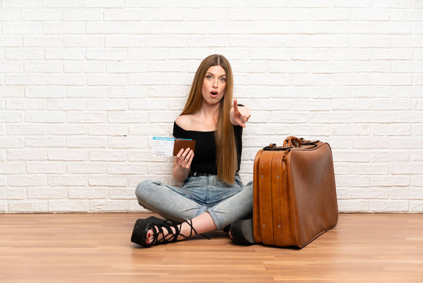 Странствующая женщина с чемоданом и посадочным талоном удивлена и указывает фронт
 - Фото, изображение