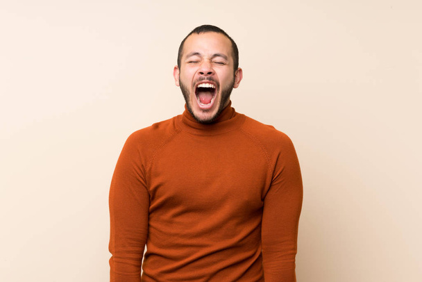 Colombian man with turtleneck sweater shouting to the front with mouth wide open - Photo, Image