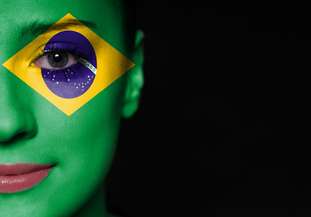 Portret van een vrouw met de vlag van de Brazilië geschilderd op haar gezicht - Foto, afbeelding