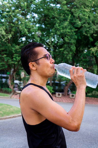Hombre deportivo bebiendo botella de agua después del entrenamiento en el parque. concepto saludable
. - Foto, Imagen