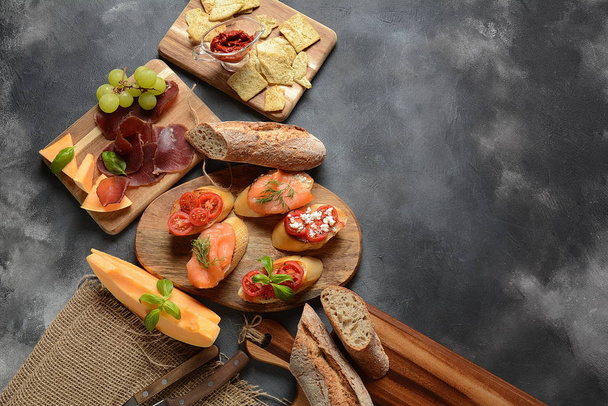 Brushetta or traditional Spanish tapas. Appetizers with Italian antipasti snacks. Variety of small sandwiches with cherry tomatoes, salmon, cream cheese. Prosciutto served with melon and basil - Foto, Imagem