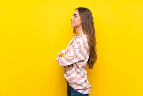 Junge Frau über isoliertem gelben Hintergrund in Seitenlage - Foto, Bild