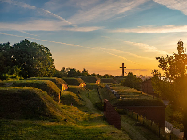 Imponujące stare fortyfikacje i pomnik Millennium Cross na wzgórzu gradowa w Gdańsku przy wschodzie słońca. - Zdjęcie, obraz