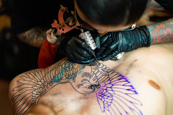 Tattoo salon process. A tattoo girl stuffed a tattoo. the process of stuffing a tattoo on the body. Hands close-up. - Foto, afbeelding
