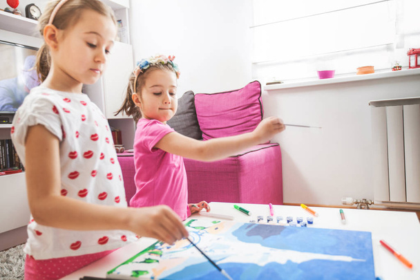  Две маленькие девочки рисуют на холсте
 - Фото, изображение