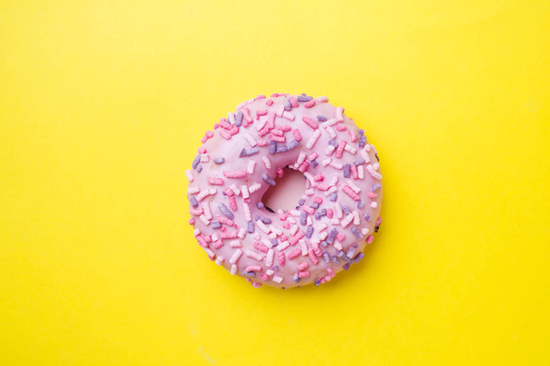 Pink doughnut on a yellow background. Top view Flat lay. - Foto, Imagem