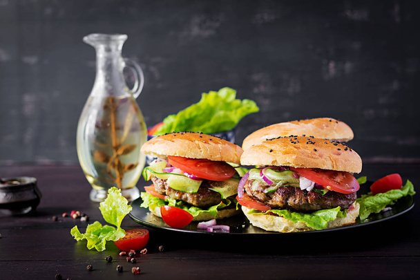 Великий бутерброд гамбургер з яловичиною, помідорами, червоною цибулею та салатом
. - Фото, зображення