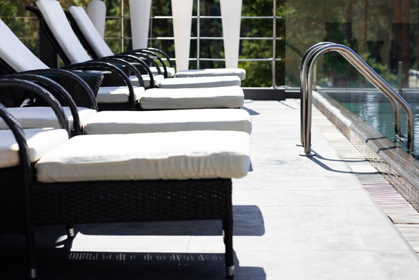 sun beds near swimming pool with railings on resort - Photo, Image