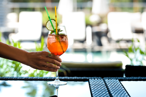 Cropped view of woman holding cocktail with mint and lemon on resort - Fotoğraf, Görsel