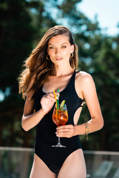 attractive sexy woman in swimming suit posing with cocktail on resort - Photo, Image