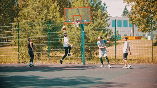 Czterech młodych mężczyzn gra w koszykówkę na boisko sportowe na zewnątrz - Zdjęcie, obraz