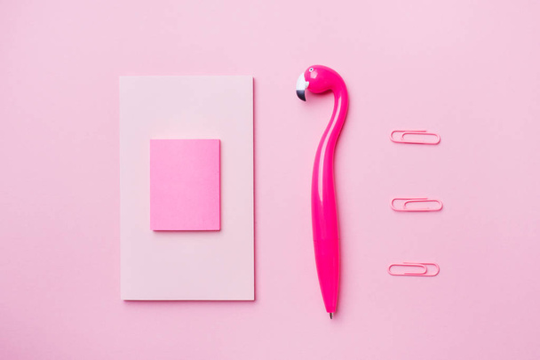 Pink Flamingo pen and writing pad on pink background. Copy space flat lay . - Foto, Imagem