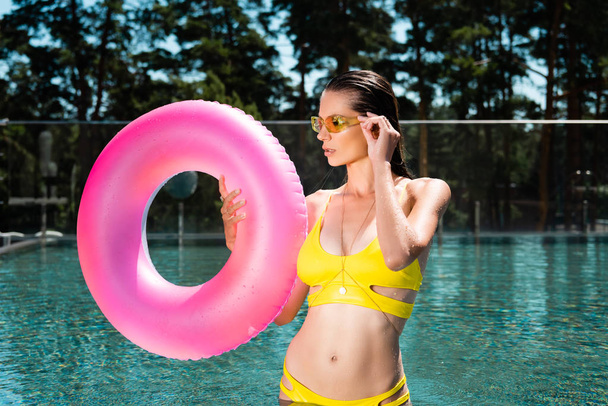 hermosa joven posando con anillo de natación en la piscina en el complejo
 - Foto, Imagen