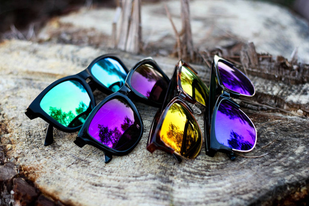 Небрендові барвисті сонцезахисні окуляри на дереві журналу
 - Фото, зображення