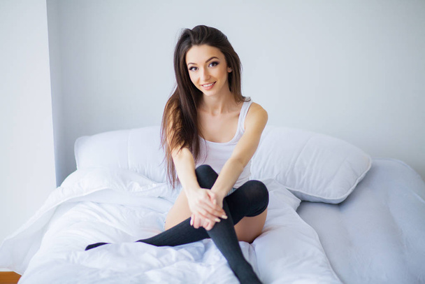 ベッドの上に座っている若い女性のショット - 写真・画像