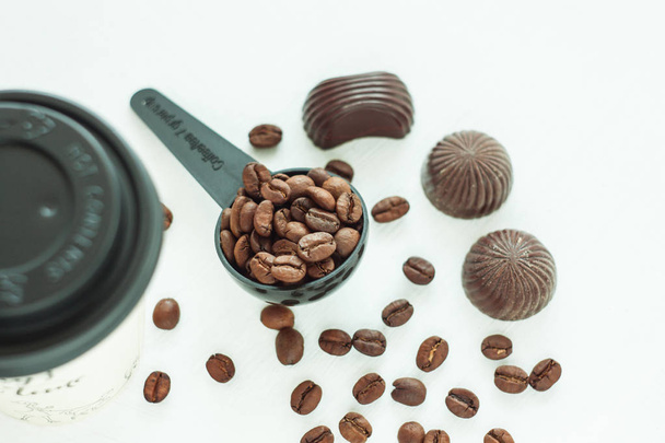 Bonbons au chocolat noir, bonbons avec une cuillère de grains de café sur fond clair. Concept de style de vie
. - Photo, image