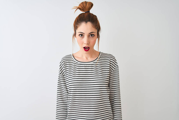 Redhead woman wearing navy striped t-shirt standing over isolated white background afraid and shocked with surprise expression, fear and excited face. - Photo, Image