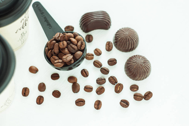 ダークチョコレートキャンディー、明るい背景にコーヒー豆のスプーンとお菓子。ライフスタイルコンセプト. - 写真・画像