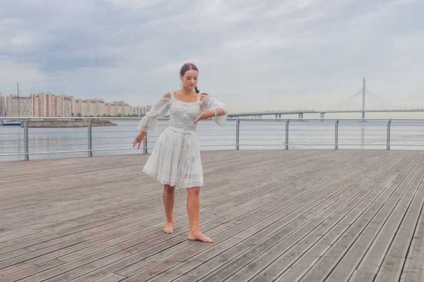 the waterfront girl in a white dress dancing - Foto, Imagen