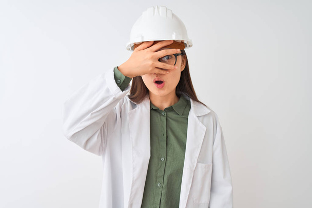 Молодий китайський інженер жінка носіння окуляри шолома в ізольованому білому фоні заглядати в шок покриття обличчя і очей з боку, переглядаючи пальці з ніяково вираз. - Фото, зображення