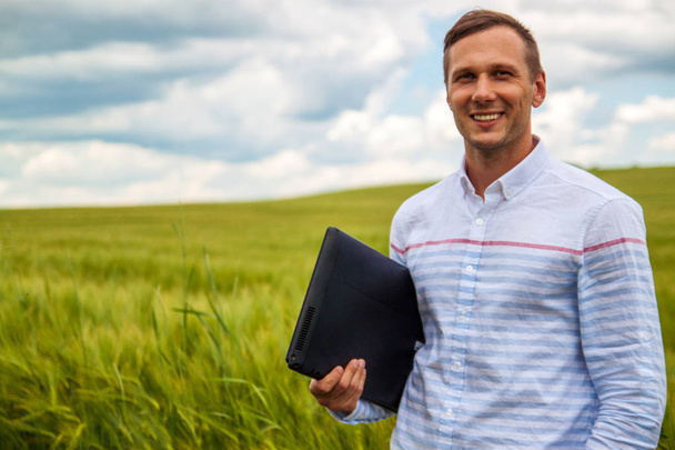 homme d'affaires utilisant un ordinateur portable et smartphone dans le champ de blé
. - Photo, image