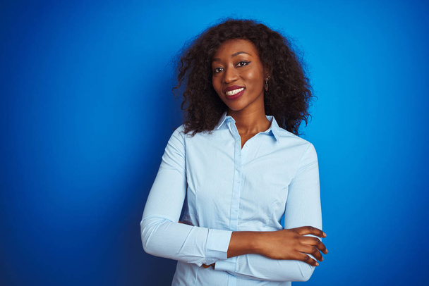 African american businesswoman wearing shirt standing over isolated blue background happy face smiling with crossed arms looking at the camera. Positive person. - Photo, Image