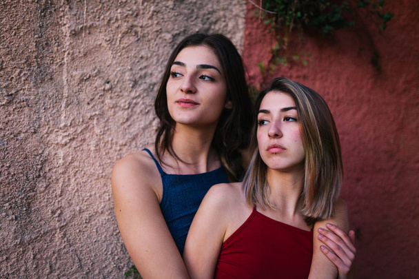 Dos mujeres jóvenes ven el atardecer desde la pared de dos colores
 - Foto, Imagen