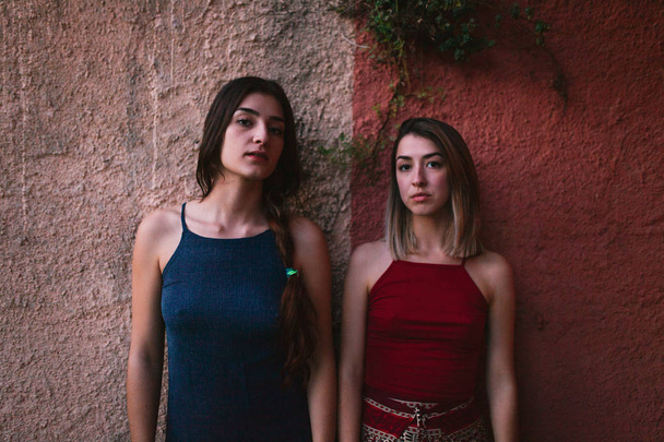 Dos mujeres jóvenes ven el atardecer desde la pared de dos colores
 - Foto, imagen