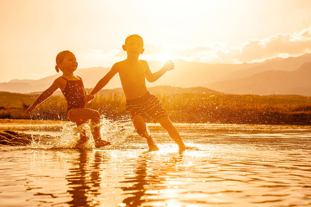 retrato de dos niños de 3 y 6 años jugando en el mar y spr
 - Foto, imagen
