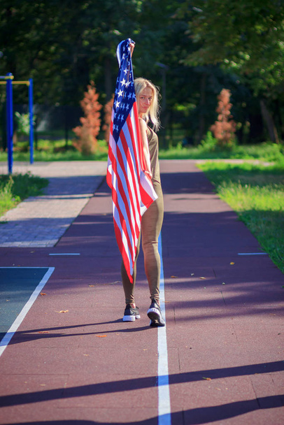 Спорт: молода жінка в спортивному одязі з американським прапором. - Фото, зображення
