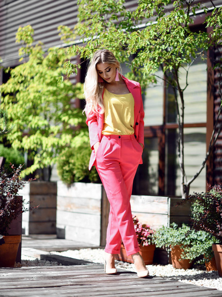 Successful young blonde woman in modern pink jacket suit and yellow blouse  - Photo, Image