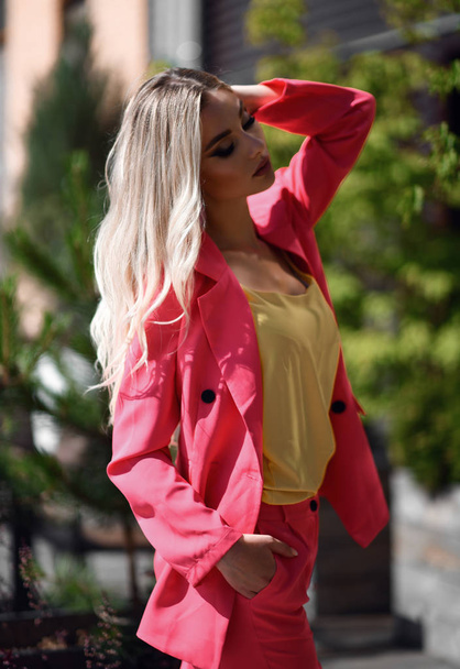 Successful young blonde woman in modern pink jacket suit and yellow blouse  - Foto, Imagen