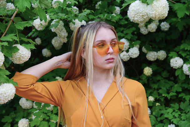 Portrait of a teenage girl in orange glasses on the background of hydrangea. - Foto, Imagen