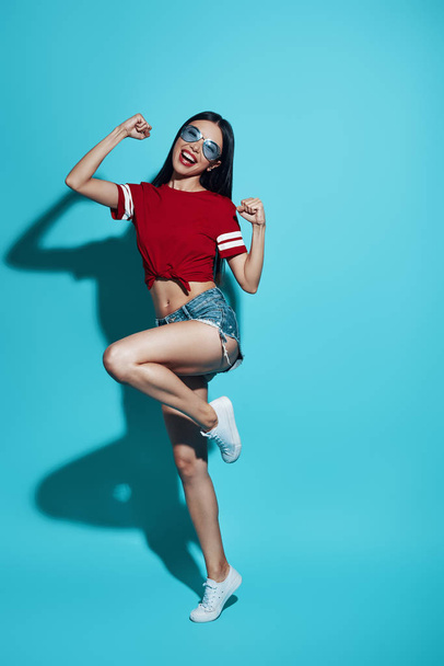Totalmente despreocupado. Comprimento completo atraente jovem mulher asiática sorrindo e dançando enquanto está de pé contra fundo azul
 - Foto, Imagem