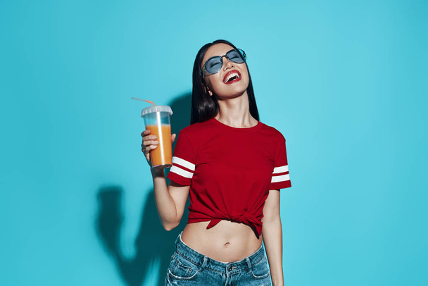Cheers to summer! Attractive young Asian woman smiling while standing against blue background - Fotografie, Obrázek