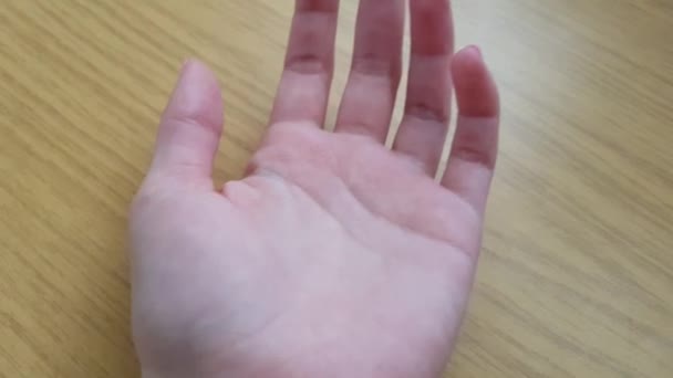 offene weibliche Handfläche und Finger mit weißer Haut auf einem Holztisch liegend, Nahaufnahme - Filmmaterial, Video