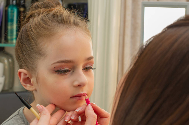 una niña haciendo maquillaje antes de actuar en el escenario. Preparación antes de la actuación en el vestidor
 - Foto, Imagen
